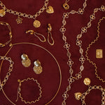 Gouden BLOSS Essentials met Solene en Ovelle oorbellen en Odine sieraden op bordeauxrode stof
