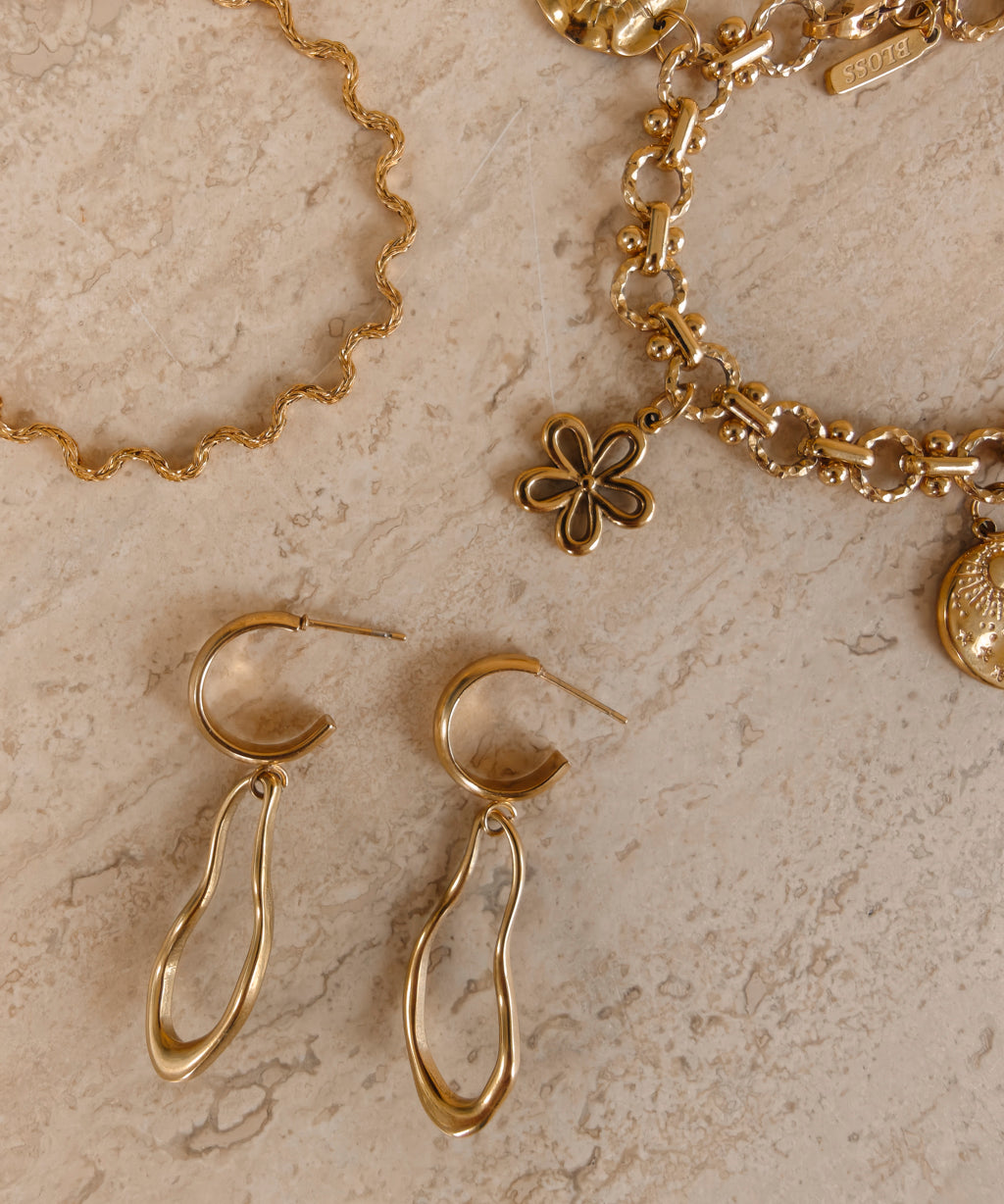 Ovelle oorbellen naast gouden Coquette en Odine sieraden