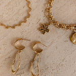 Ovelle oorbellen naast gouden Coquette en Odine sieraden