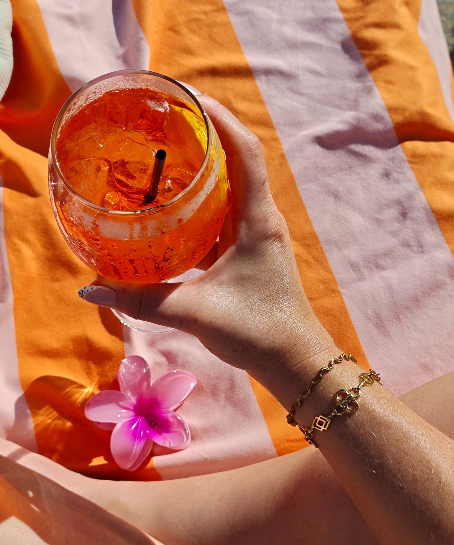 Odine Armband gecombineerd met andere gouden armbanden bij een oranje drankje